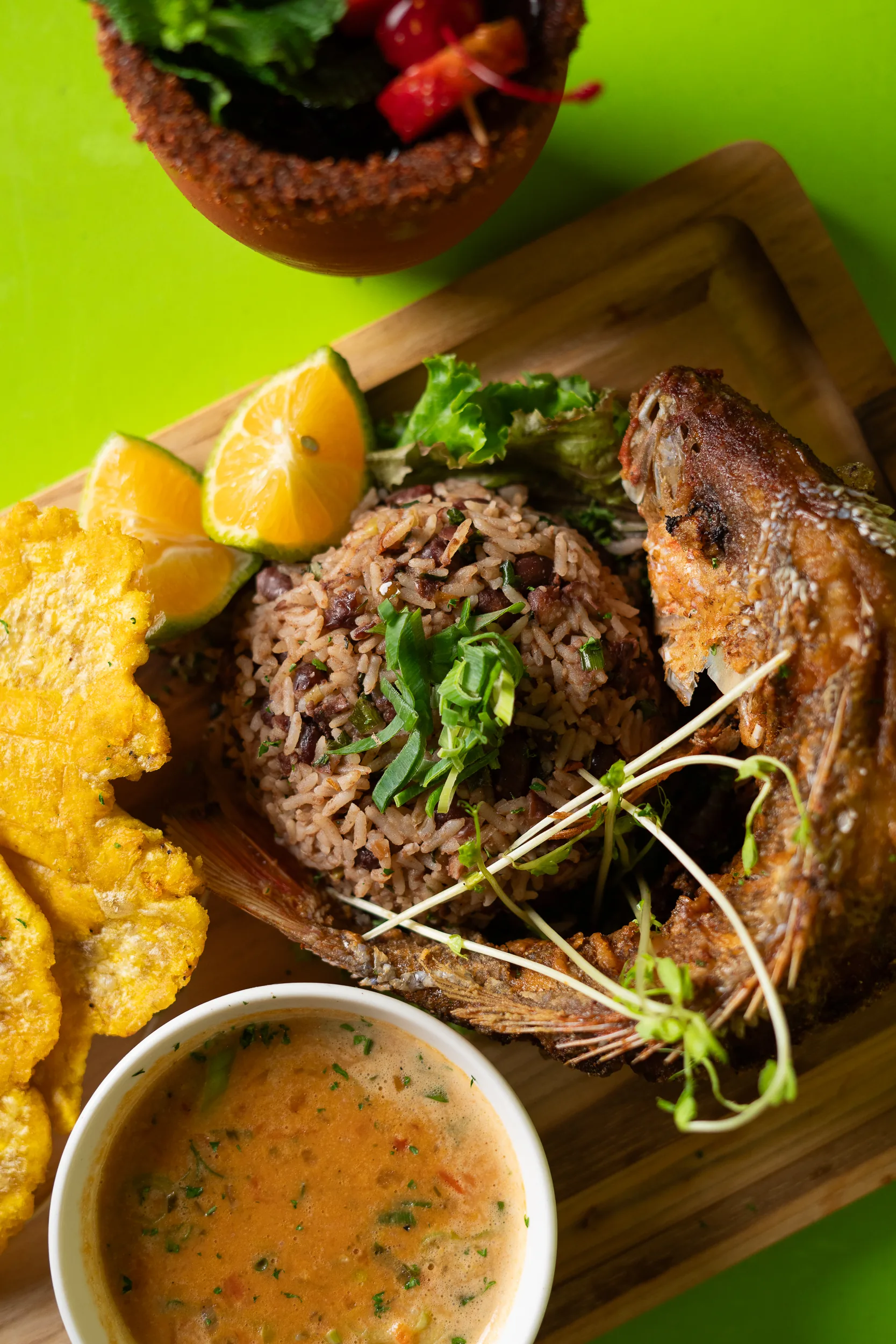 Plato de pescado con arroz, tostones y cóctel